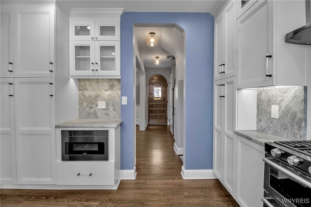 kitchen with wall chimney range hood, dark wood-style flooring, baseboards, and white cabinetry