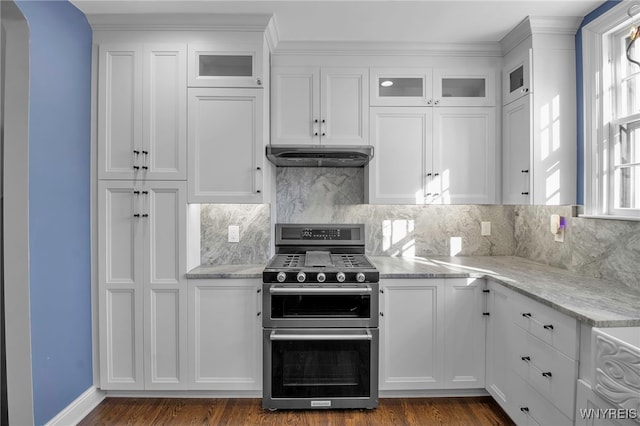 kitchen featuring glass insert cabinets, backsplash, white cabinets, under cabinet range hood, and range with two ovens