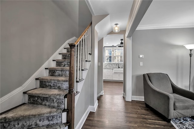 staircase with wood finished floors, baseboards, and ornamental molding