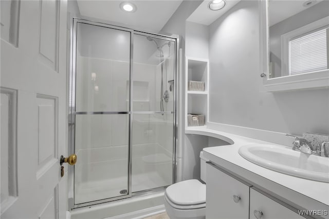 bathroom with a shower stall, vanity, and toilet