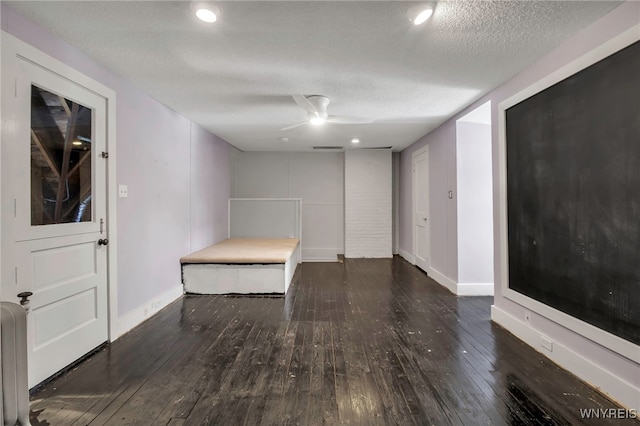 interior space with baseboards, a ceiling fan, hardwood / wood-style floors, and a textured ceiling