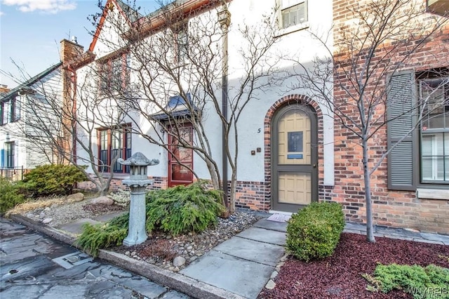 doorway to property with stucco siding and a chimney