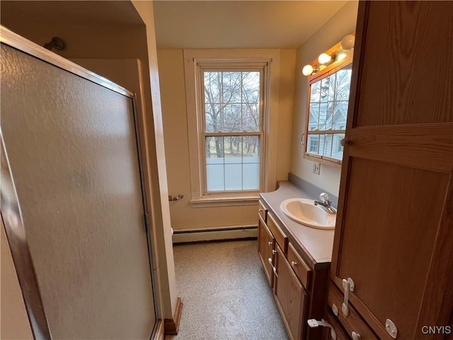bathroom featuring a baseboard radiator, vanity, baseboards, and a stall shower