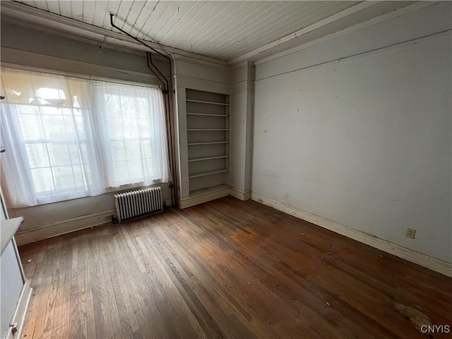spare room featuring hardwood / wood-style flooring, baseboards, and radiator