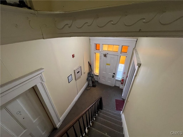 staircase featuring baseboards and carpet floors