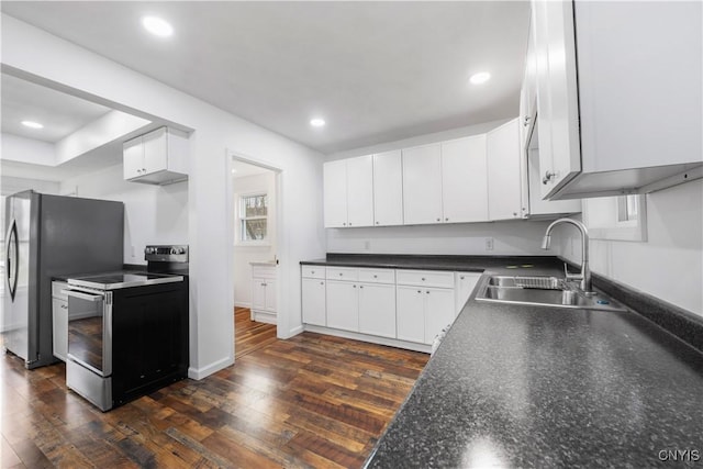 kitchen with white cabinets, dark wood-style flooring, dark countertops, a sink, and electric range oven
