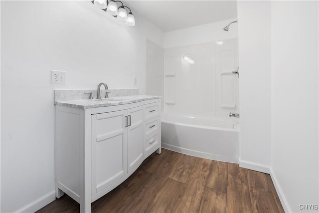 bathroom with shower / bath combination, baseboards, wood finished floors, and vanity