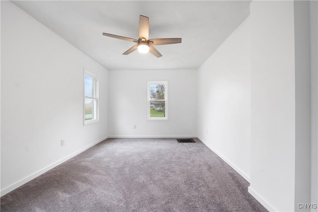 carpeted spare room with baseboards, ceiling fan, and visible vents