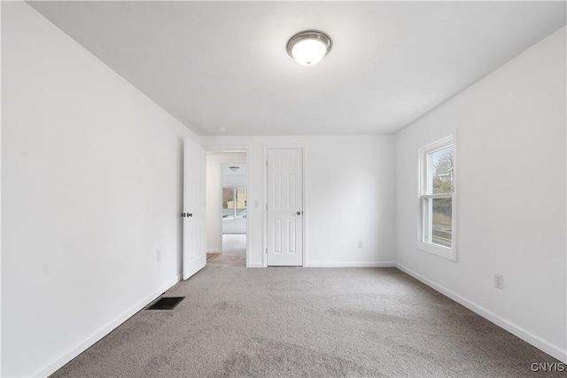 empty room with visible vents, carpet, and baseboards