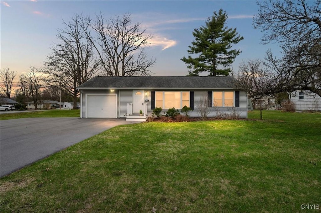 single story home featuring an attached garage, driveway, and a lawn