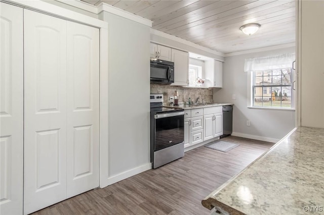 kitchen with tasteful backsplash, baseboards, ornamental molding, light countertops, and black appliances