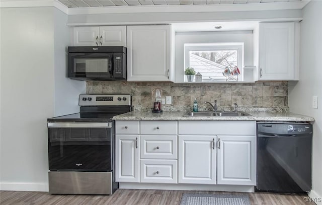 kitchen with a sink, light wood-style floors, black appliances, white cabinetry, and decorative backsplash