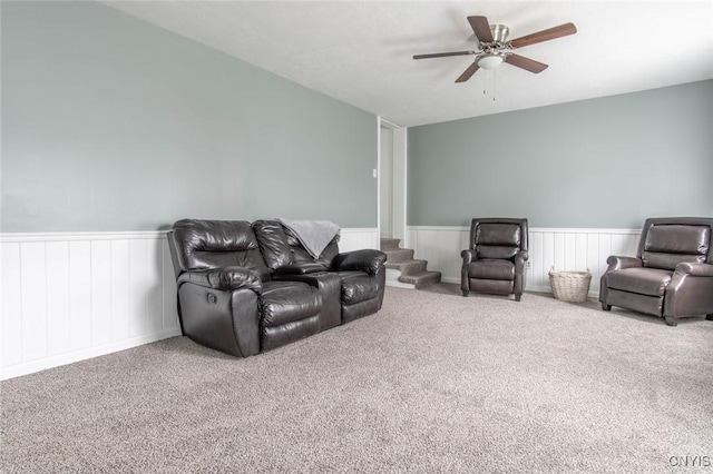 carpeted living area with wainscoting and a ceiling fan