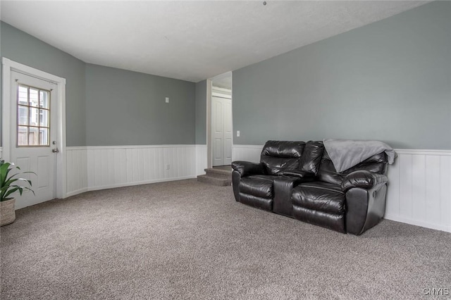 carpeted living area with a wainscoted wall
