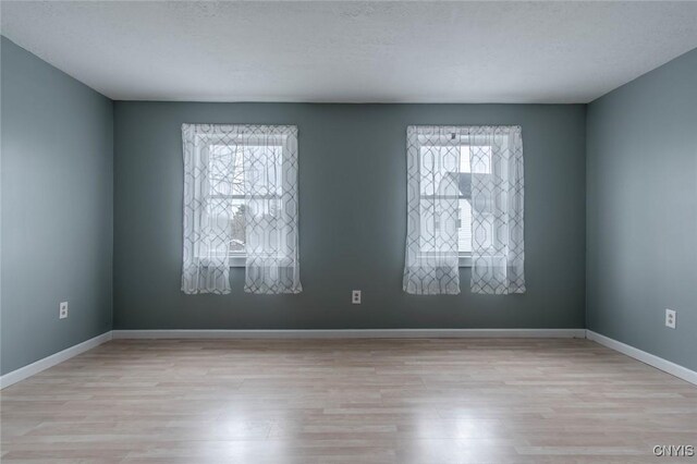 spare room featuring baseboards and wood finished floors