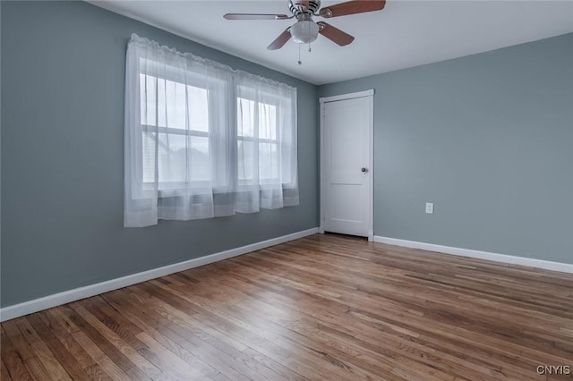 empty room featuring baseboards, a ceiling fan, and wood finished floors