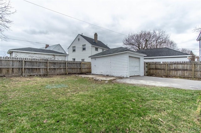 view of yard with an outbuilding, a fenced backyard, and concrete driveway