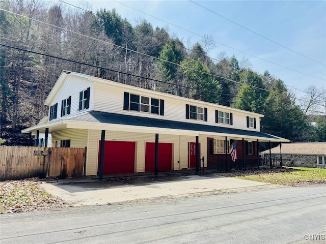 view of front of home with an attached garage, fence, driveway, and a porch