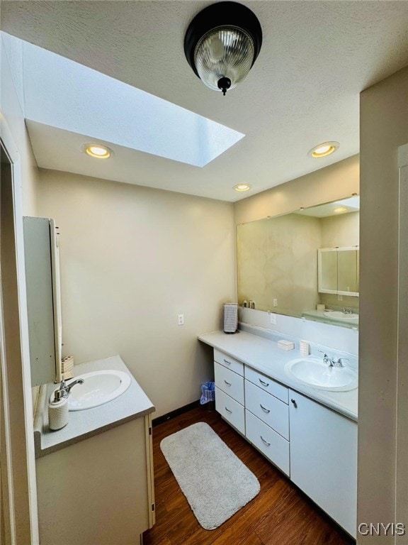 full bathroom featuring two vanities, wood finished floors, and a sink