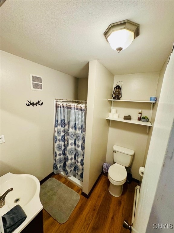 full bathroom featuring visible vents, a shower with shower curtain, toilet, vanity, and wood finished floors