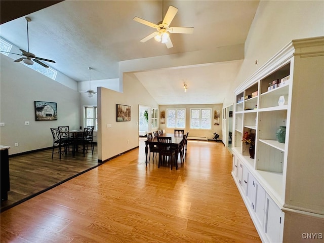 dining room with ceiling fan, light wood finished floors, high vaulted ceiling, and baseboards
