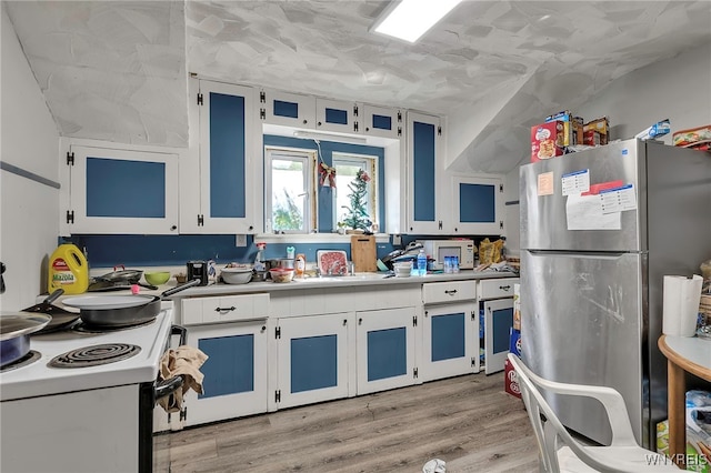 192 Pine St, Lockport City, NY 14094 - kitchen featuring light wood-type flooring, light countertops, freestanding refrigerator, white cabinetry, and white range with electric stovetop