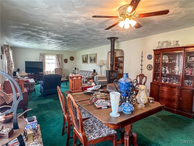 dining room featuring a wood stove, carpet, and ceiling fan