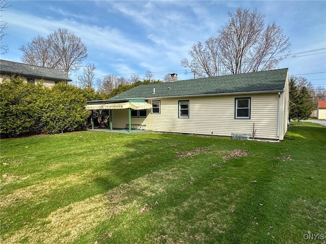 back of house featuring a chimney, a patio area, and a lawn