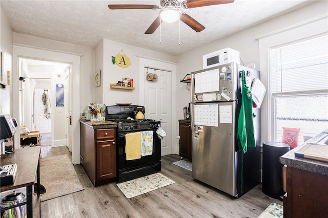 kitchen featuring light wood-style floors, freestanding refrigerator, a textured ceiling, a ceiling fan, and black gas stove