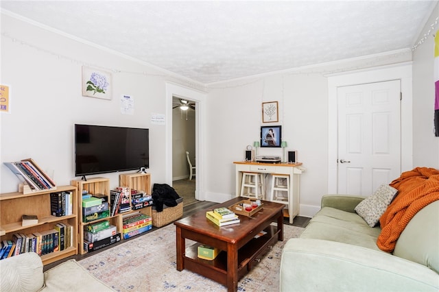 living area featuring a ceiling fan, a textured ceiling, baseboards, and ornamental molding