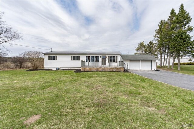 view of front of house featuring a front lawn, a deck, a garage, and driveway
