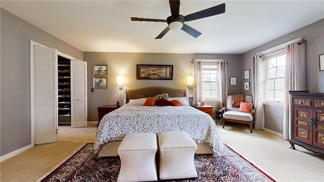 bedroom featuring light colored carpet, baseboards, and a ceiling fan