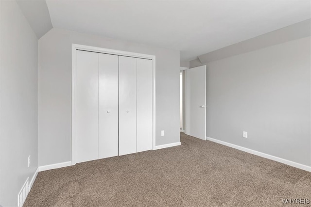unfurnished bedroom with a closet, baseboards, visible vents, carpet floors, and lofted ceiling