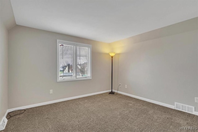 carpeted spare room featuring visible vents, baseboards, and lofted ceiling