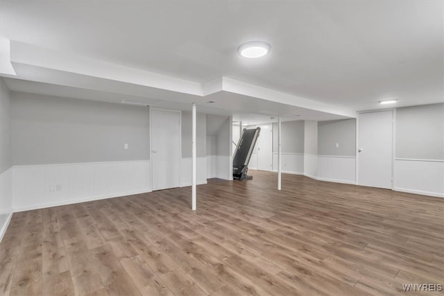finished below grade area with a wainscoted wall and wood finished floors