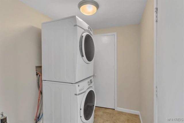 clothes washing area featuring laundry area, baseboards, and stacked washer and clothes dryer