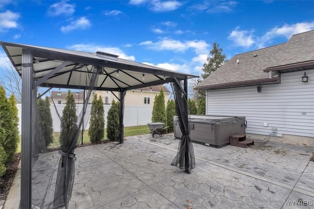 view of patio featuring a gazebo, fence, and a hot tub