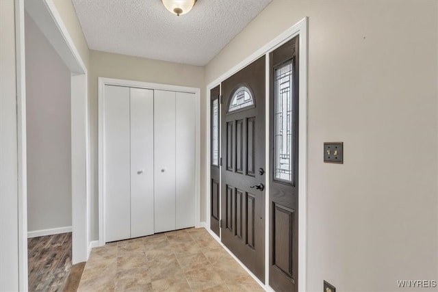entrance foyer featuring a textured ceiling and baseboards