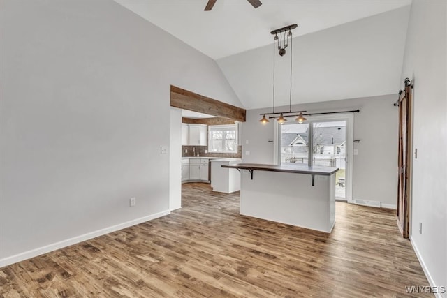 kitchen featuring pendant lighting, ceiling fan, light wood-type flooring, white cabinets, and a breakfast bar area