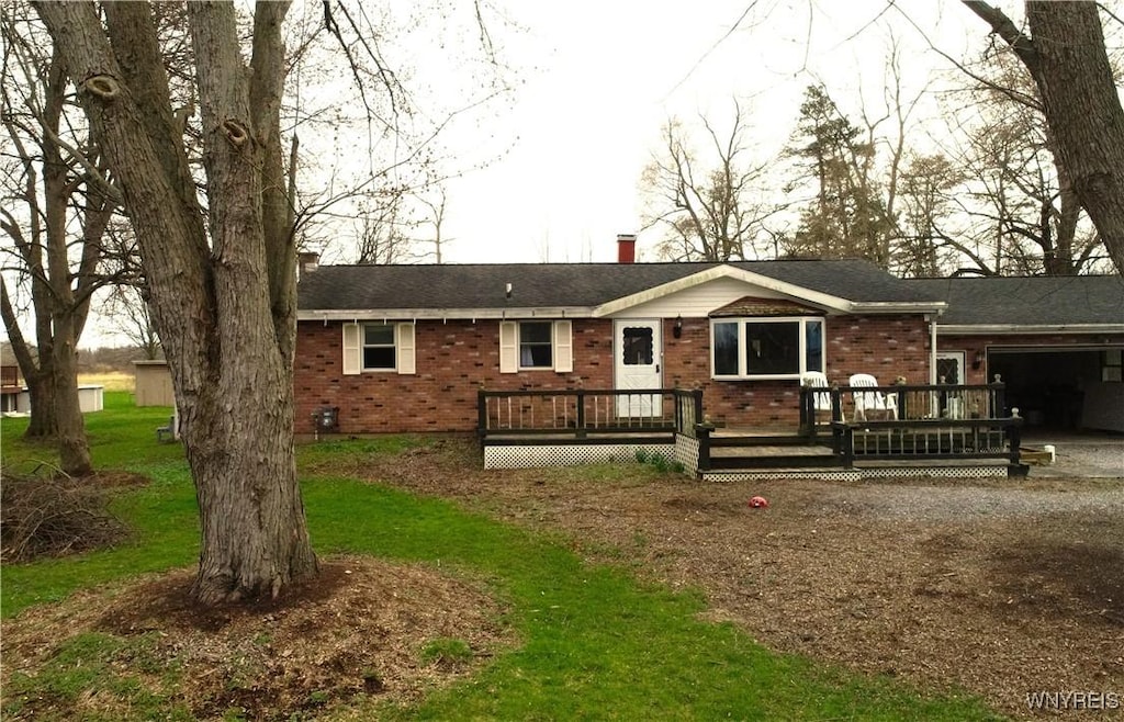 view of front facade with an attached garage, a chimney, a deck, and brick siding