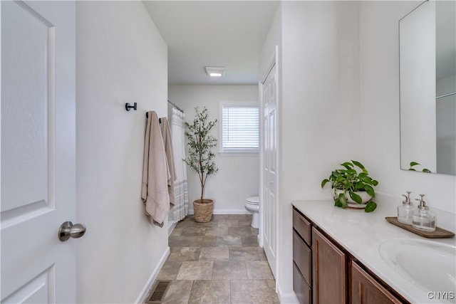 full bath with vanity, baseboards, toilet, stone finish floor, and visible vents