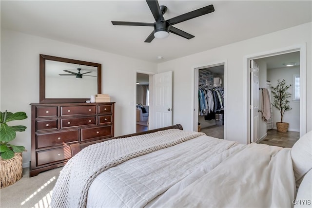 bedroom featuring a spacious closet, baseboards, a closet, and a ceiling fan