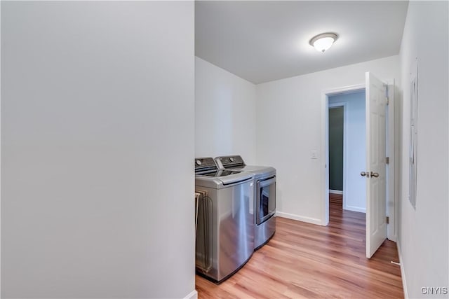 laundry area with baseboards, light wood-style flooring, laundry area, and washing machine and clothes dryer