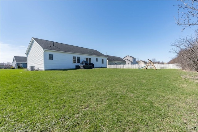 rear view of property featuring a yard, fence, and central air condition unit