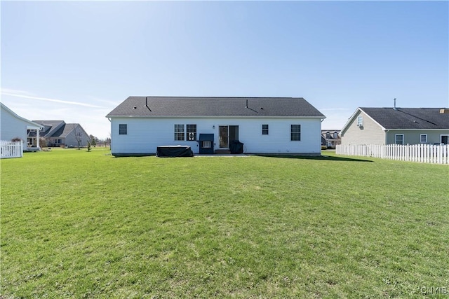 rear view of house featuring a yard and fence