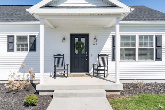 doorway to property with a porch and roof with shingles