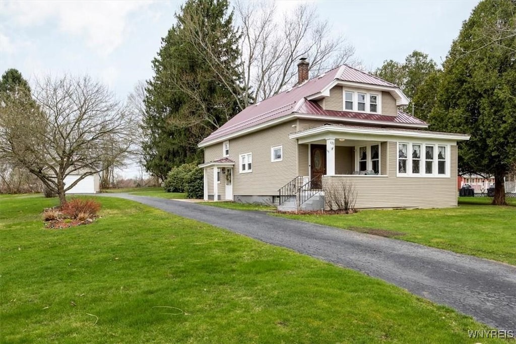 view of front of house featuring metal roof, a chimney, and a front lawn