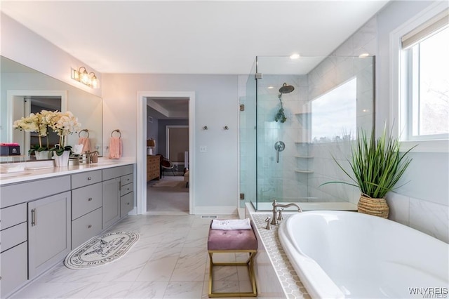 ensuite bathroom featuring a shower stall, a garden tub, vanity, marble look tile flooring, and baseboards