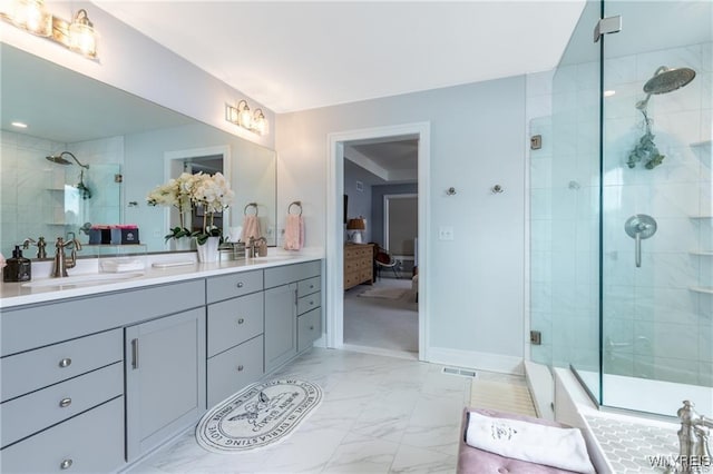 bathroom with marble look tile flooring, a stall shower, double vanity, and baseboards