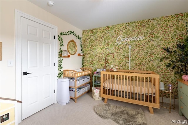 bedroom with wallpapered walls, carpet floors, and a nursery area